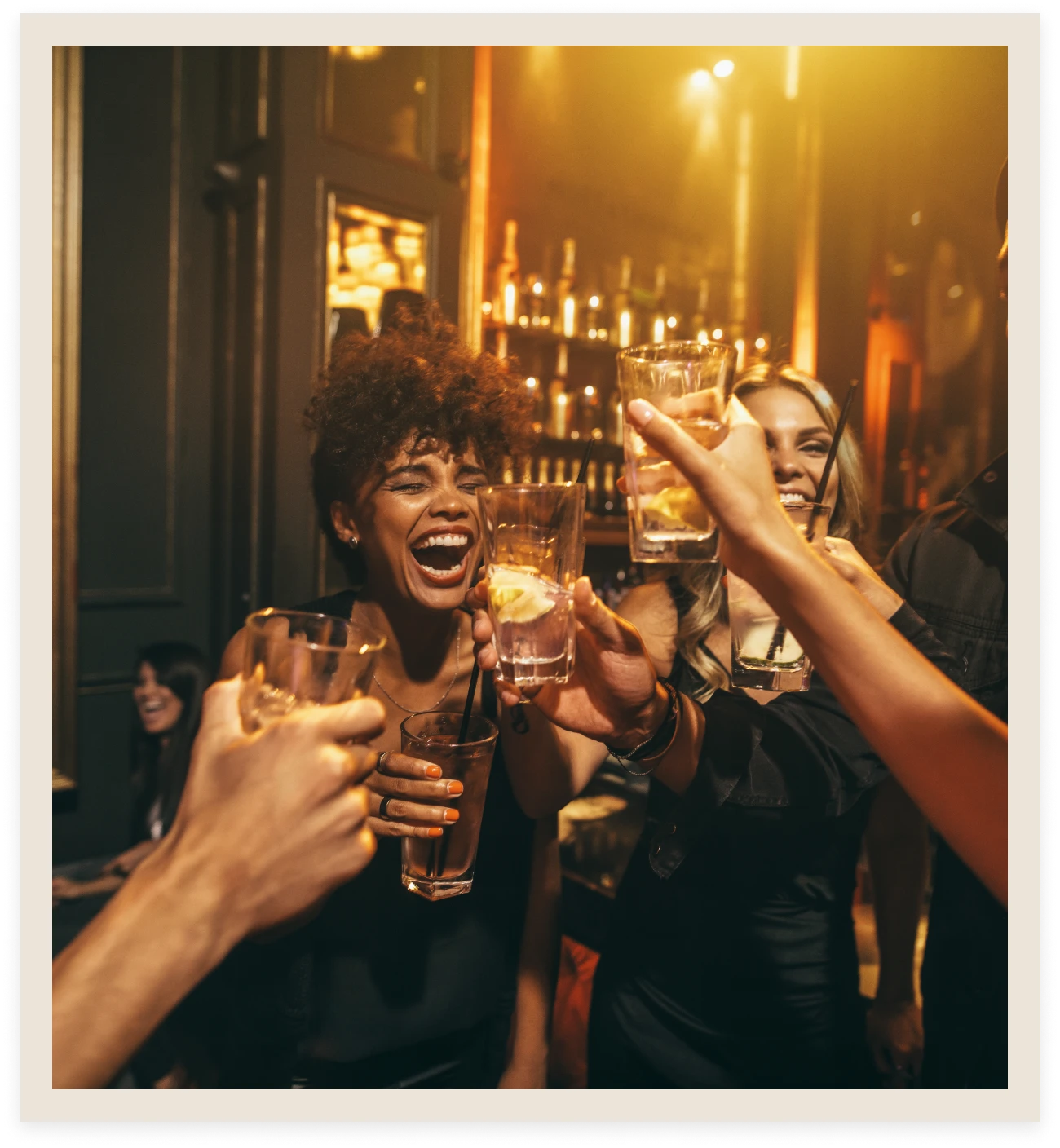 People toasting drinks in a lively bar.